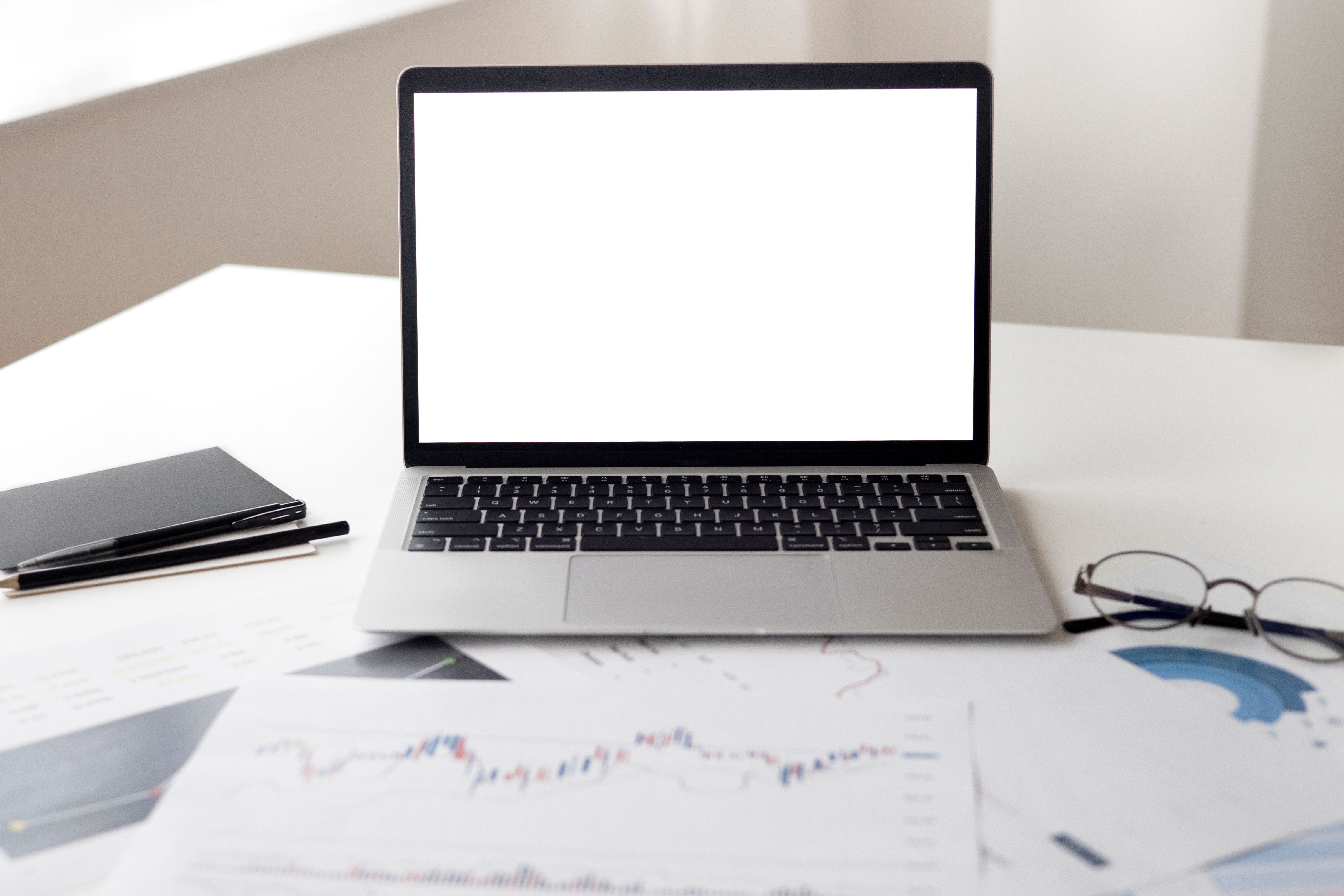 Laptop en financiële documenten op een bureau.