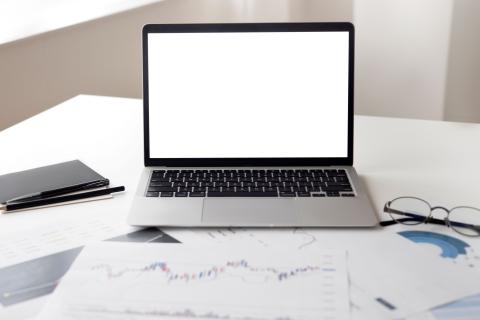 Laptop en financiële documenten op een bureau.